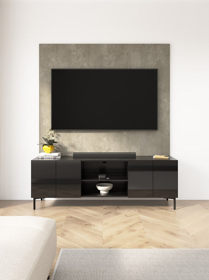 Modern black entertainment console with a television mounted on a concrete wall in a minimalistic room.