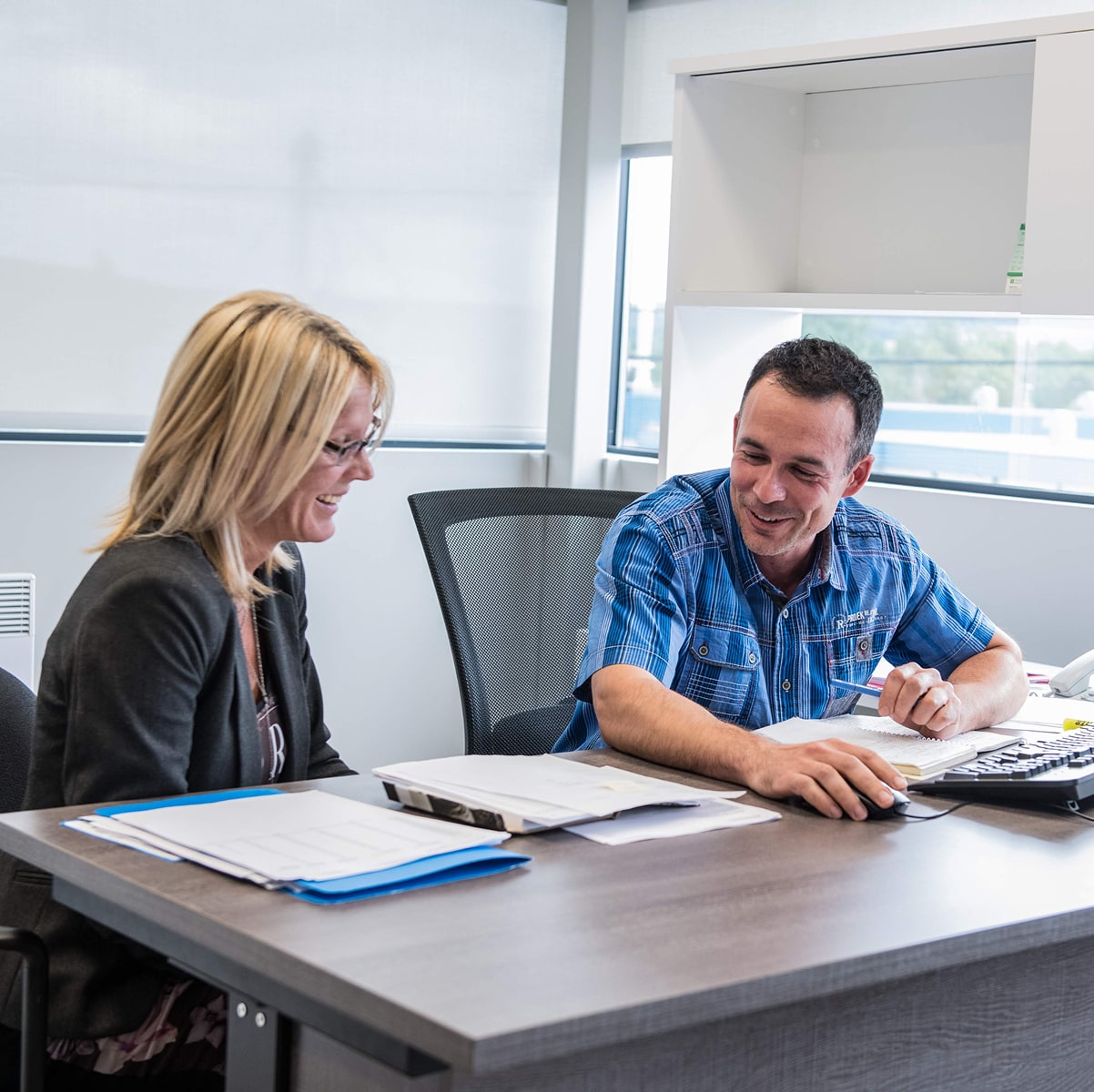Two people working at a desk in an office setting.