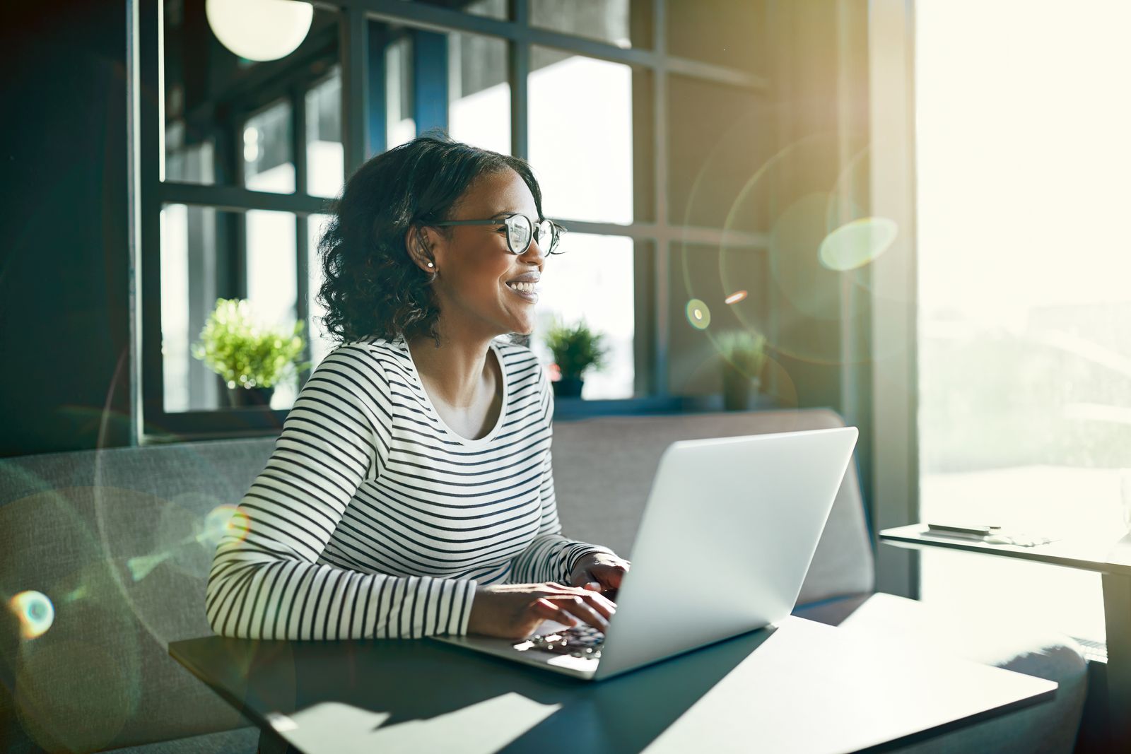 woman sitting at desk with sun coming in while she works from home