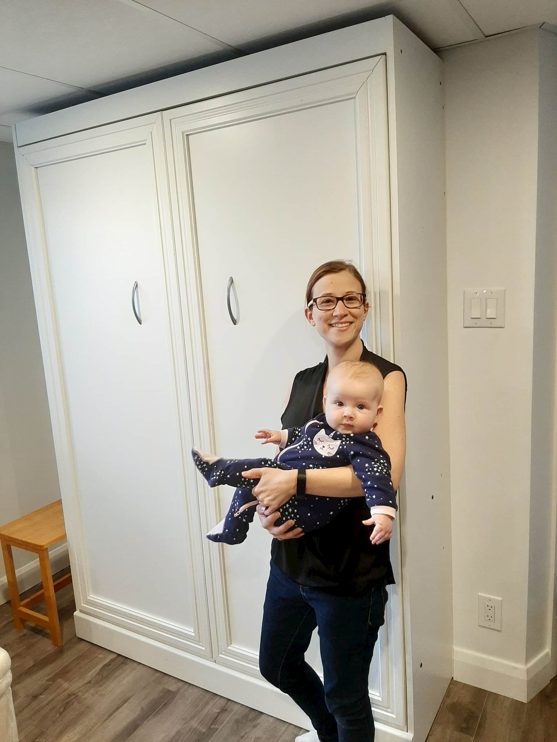 Women holding a baby next to Murphy Bed