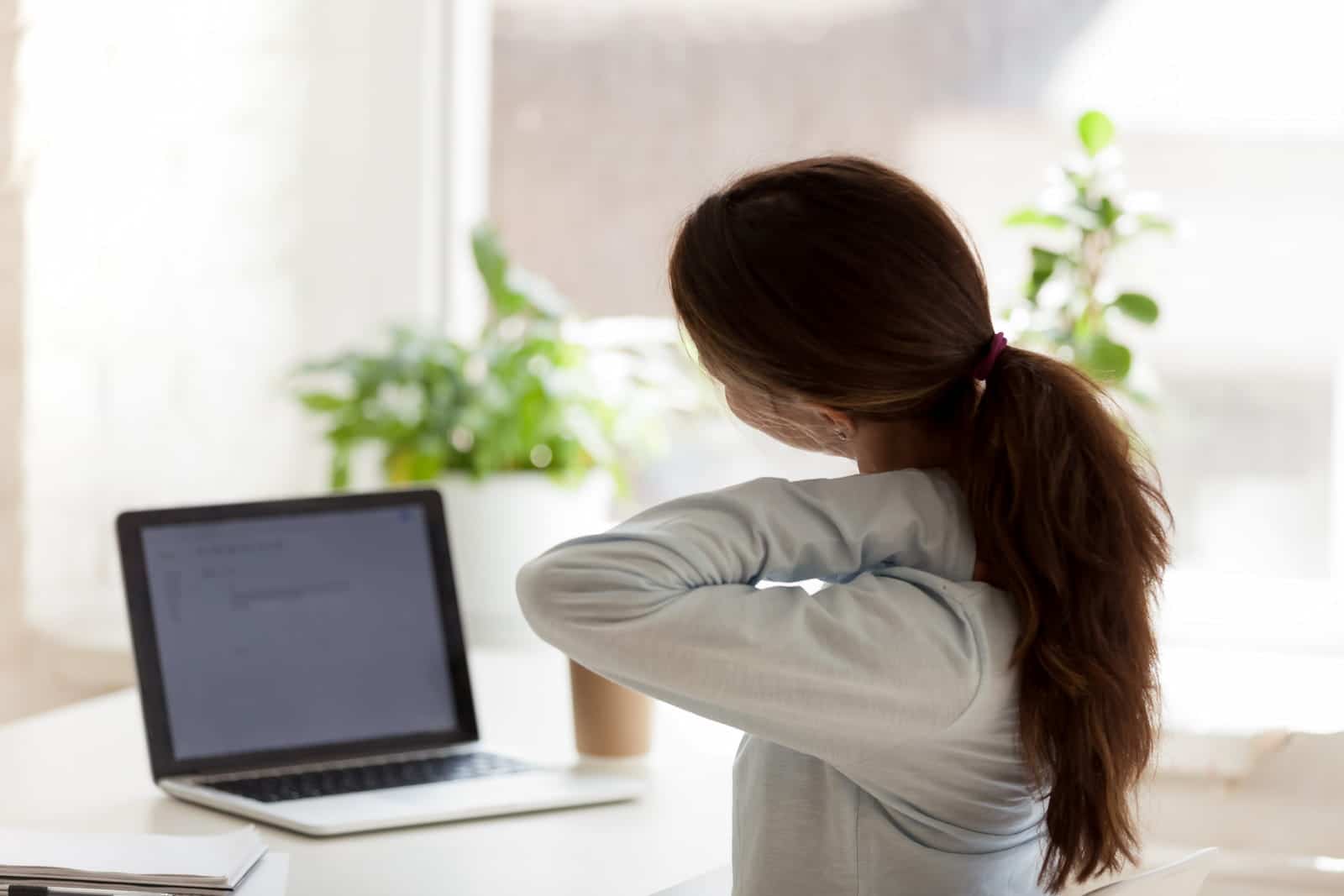 woman stretching her neck at computer