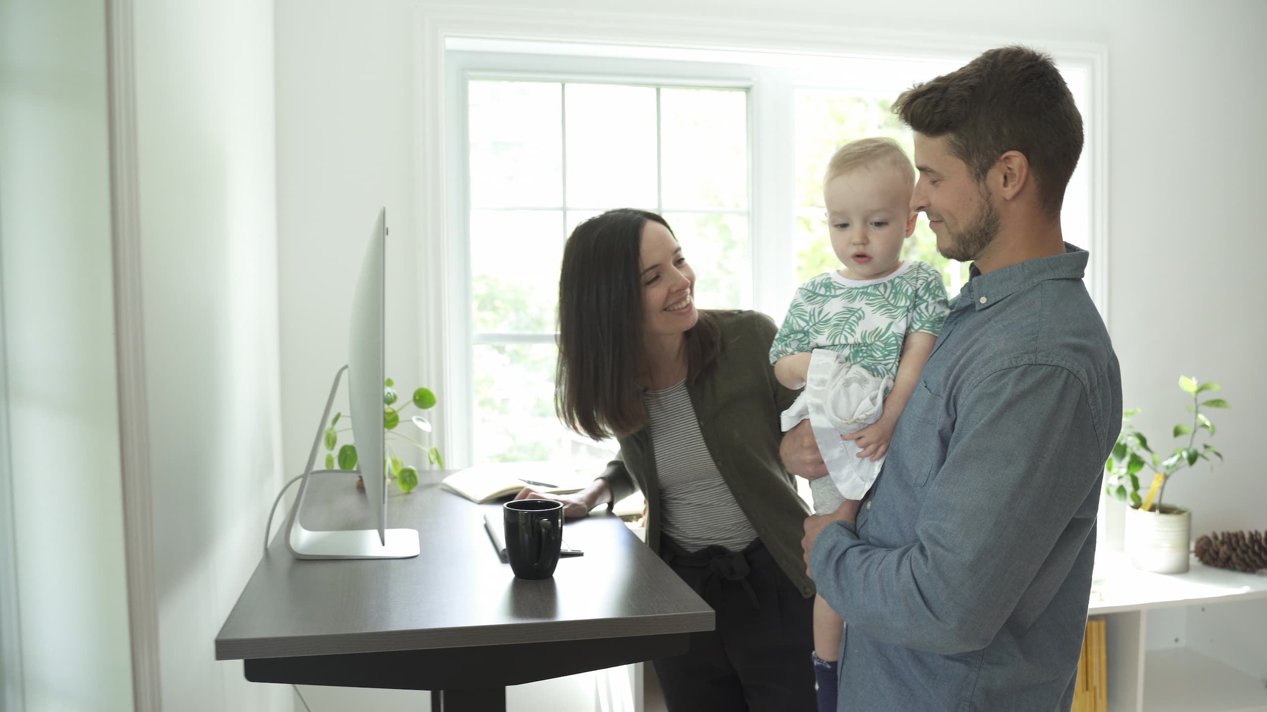 couple with baby next to standing desk