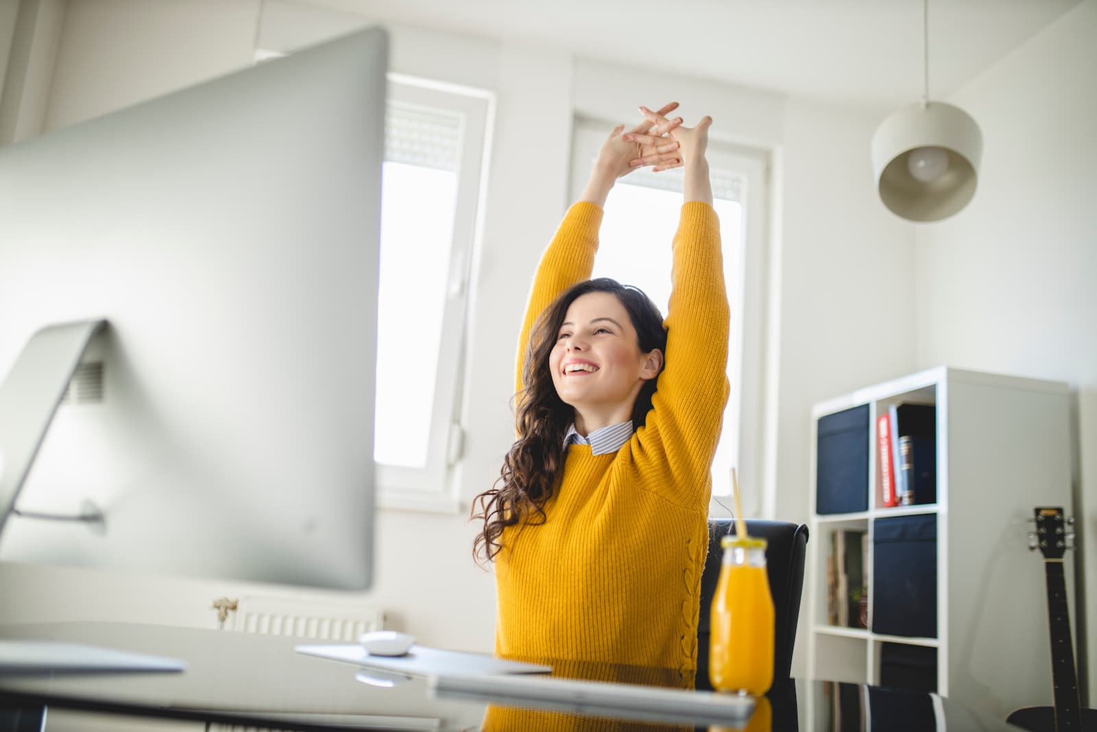 Smiling woman stretching at her desk