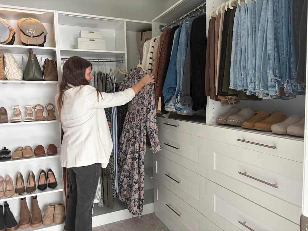 Woman selecting a dress in a walk-in closet system with open shelves and drawers