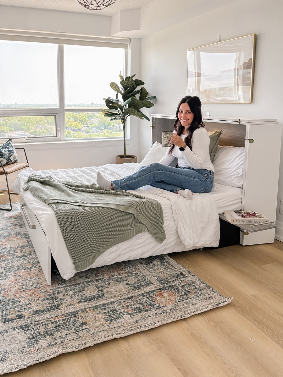 A woman resting on Borealis collection cabinet bed and holding a cup